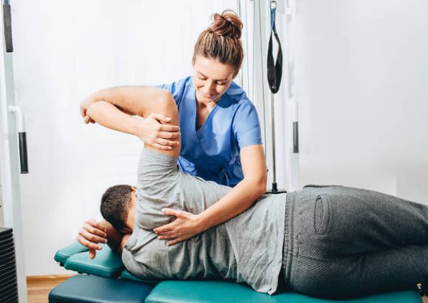 Physiotherapist treatment patient. She holding patient's hand, shoulder joint treatment